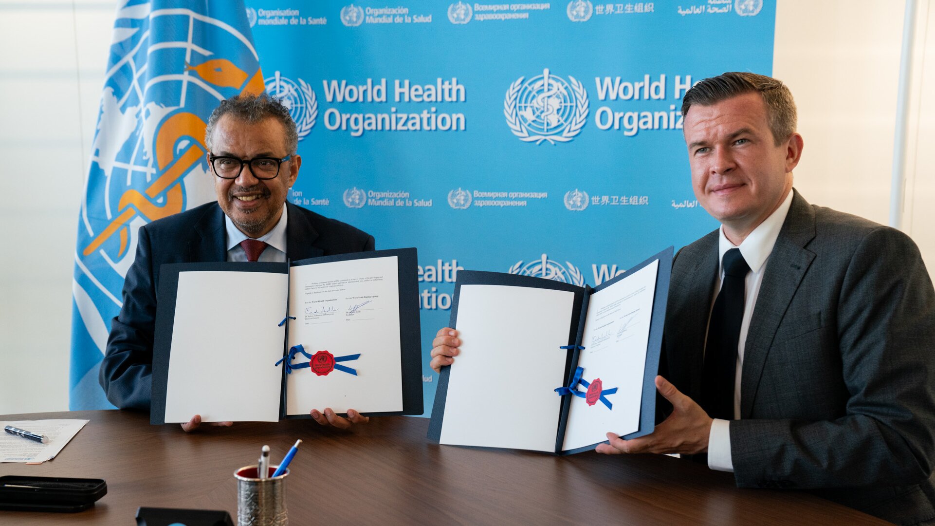WADA President, Witold Bańka, and WHO Director-General, Dr Tedros Adhanom Ghebreyesus showing signed examples of a Memory of Understanding