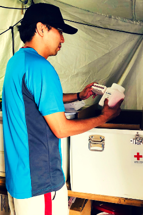 Japanese Red Cross pharmacist Yasutoro Nakazato inspects a box of medications that have just been delivered by the team 4