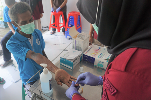 An adult man extends his hand to a healthcare worker for hepatitis C screening.